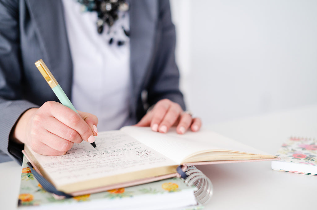 Woman in blazer writing in a notebook