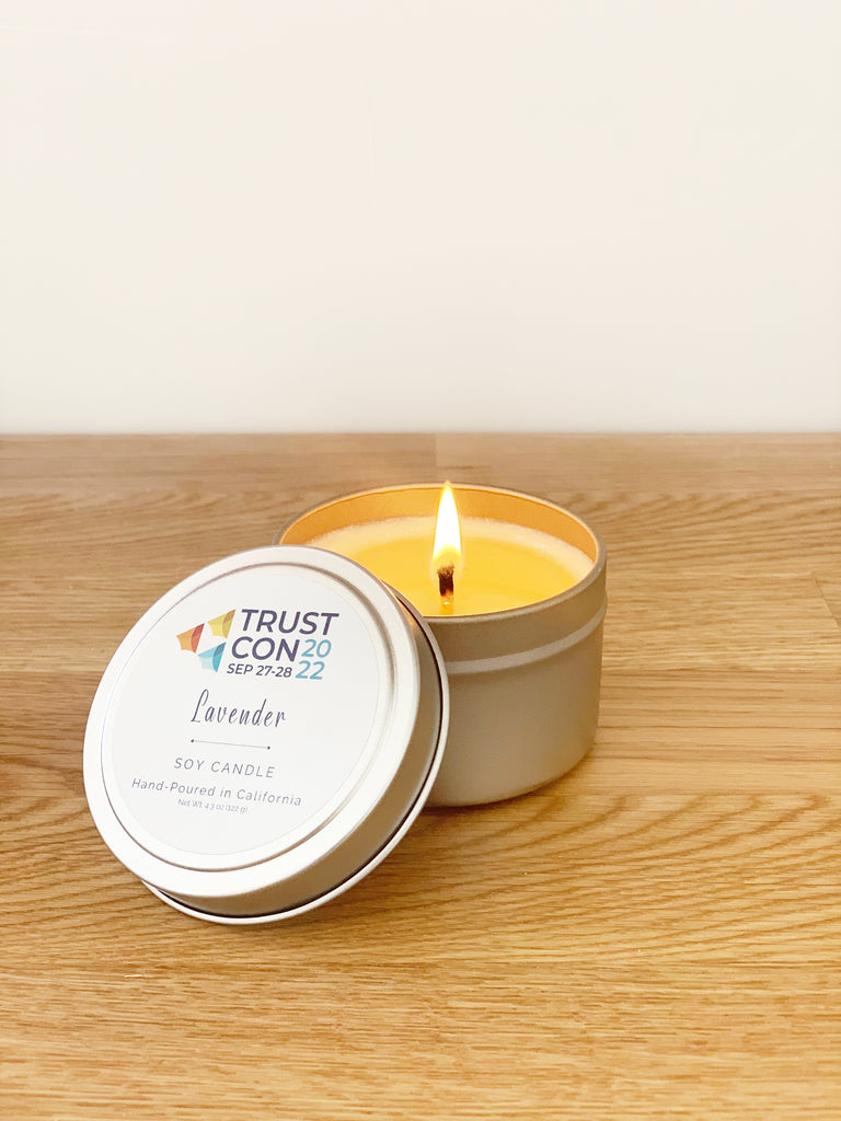 custom label travel tin candle for a corporate event in 2022. Travel tin candle is lit and sitting on a wooden counter.