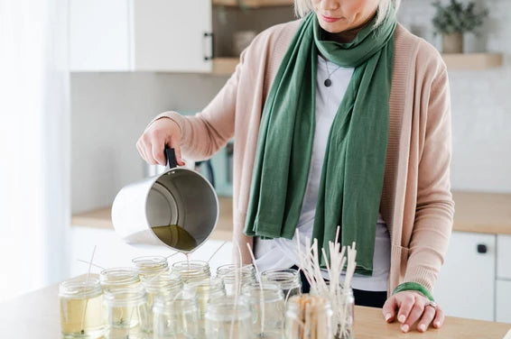 Preparing your candle order. Woman pouring soy wax from a pitcher in a candle studio. She is making hand poured soy candles. 