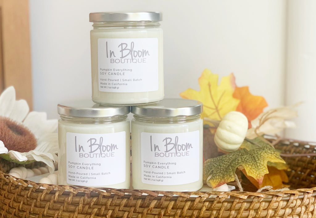 Custom Label candles for a clothing boutique called In Bloom. Fall scented candles in a basket with fall foliage
